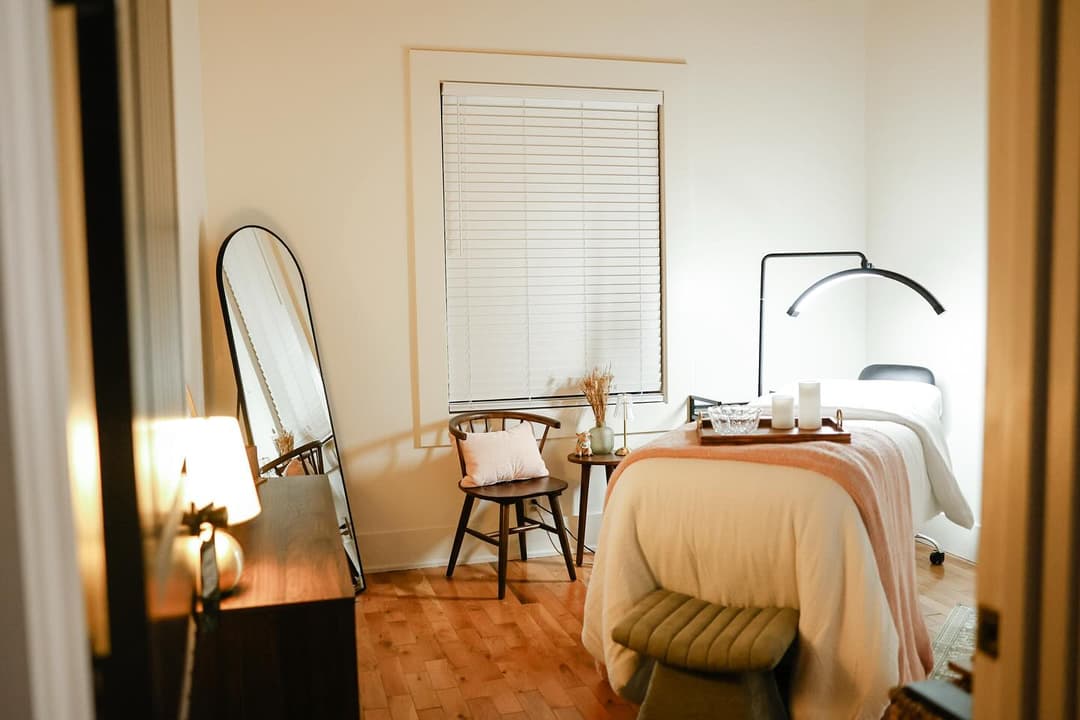 Cozy bedroom with natural lighting, mirror, and a relaxing bed setup.