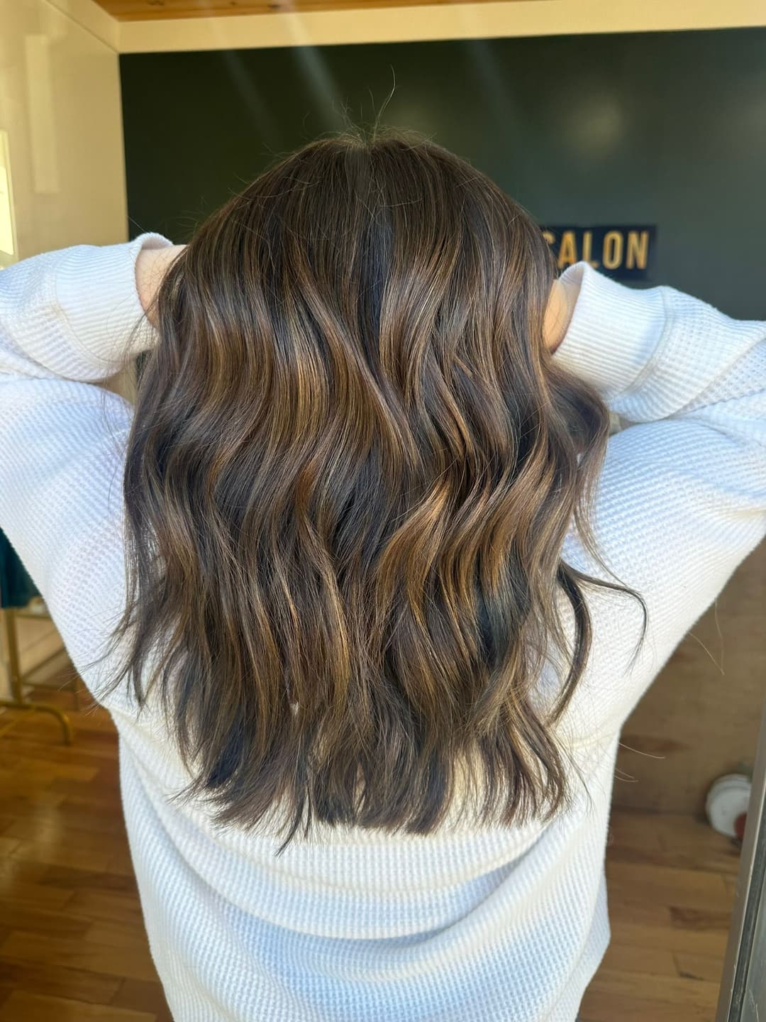 Woman with wavy, shoulder-length hair, showcasing a stylish hairstyle from behind.