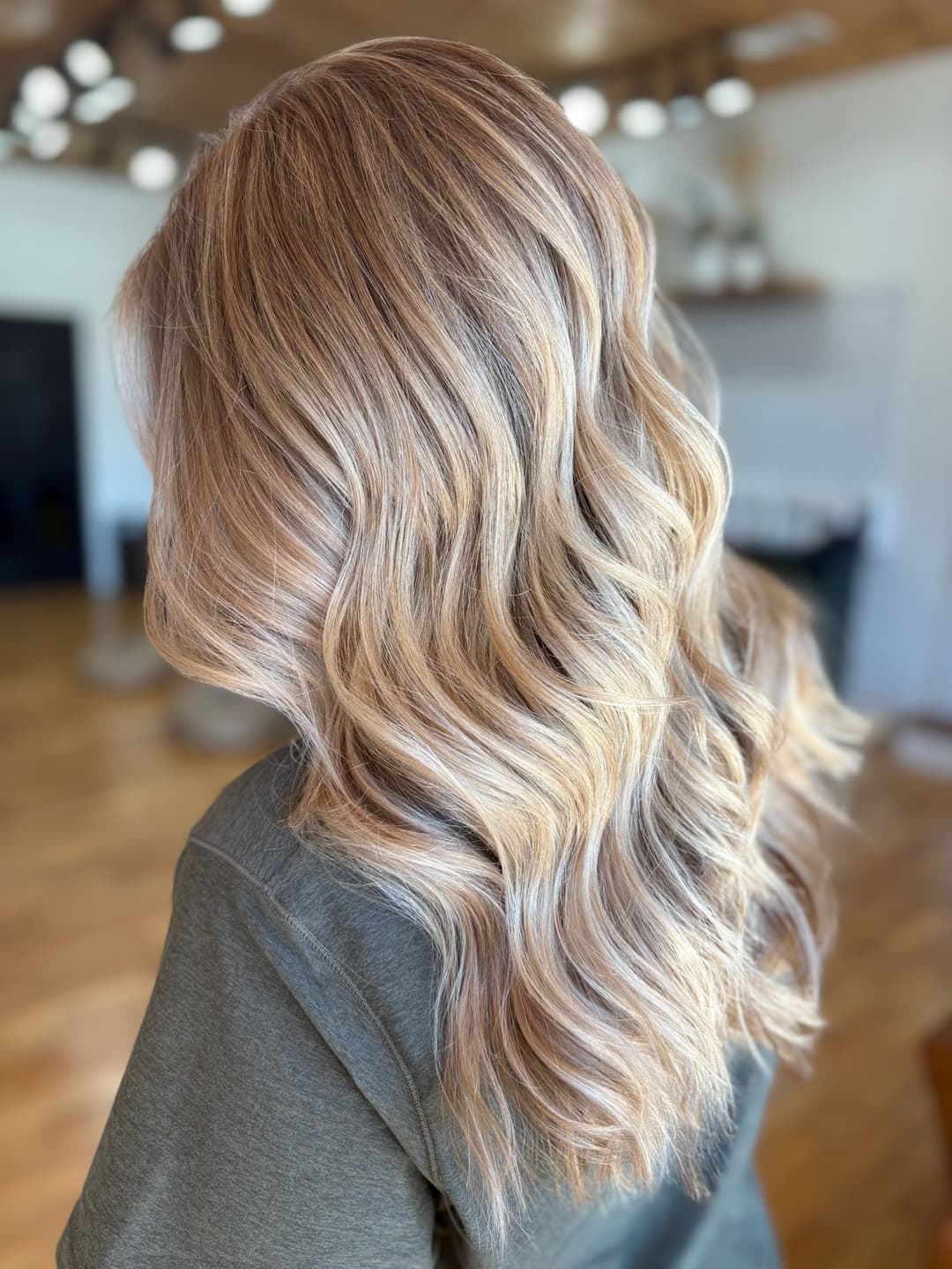 Long wavy blonde hair styled elegantly in a modern indoor setting.