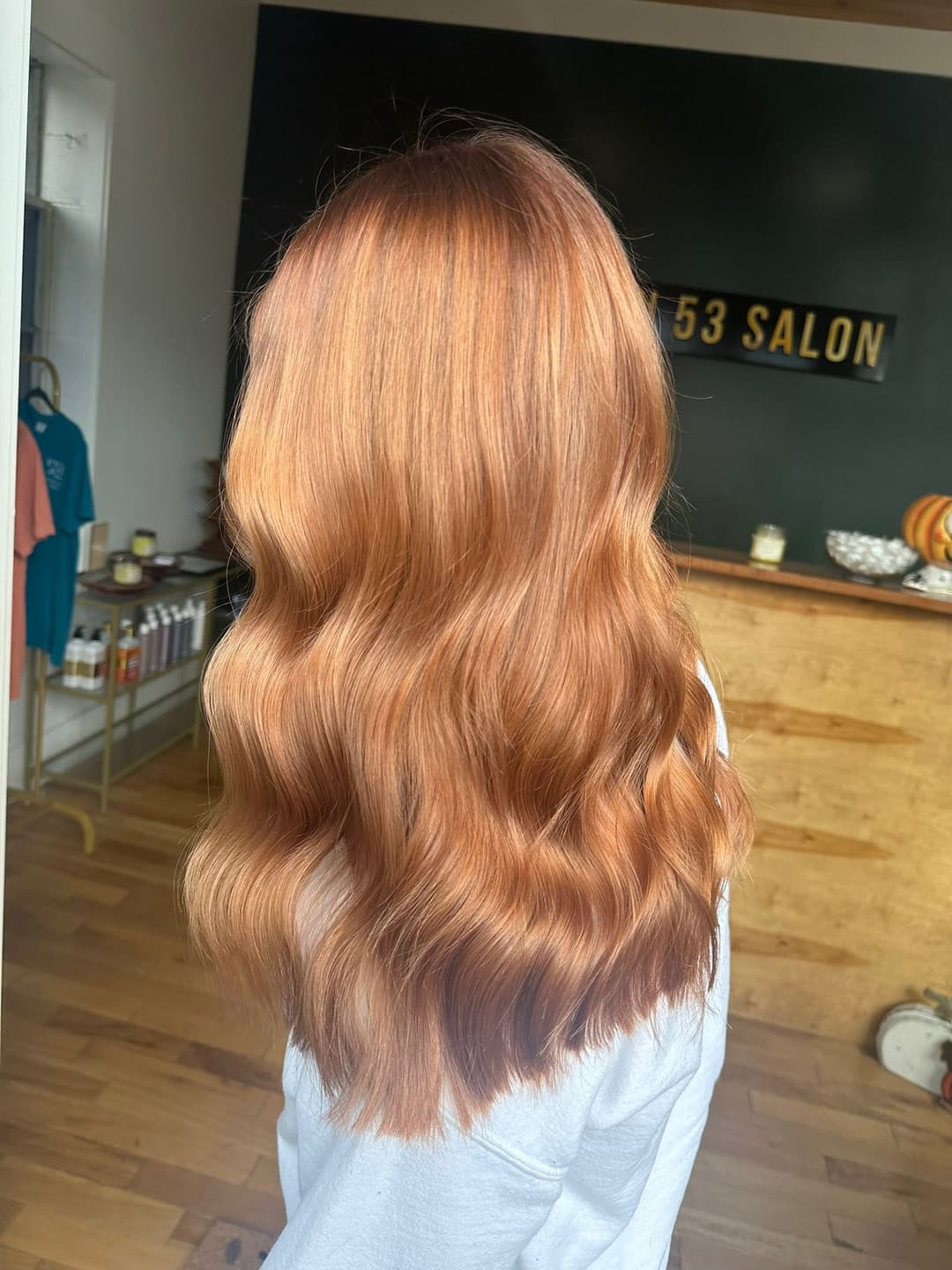 Long wavy hair with a warm copper tone in a salon setting.