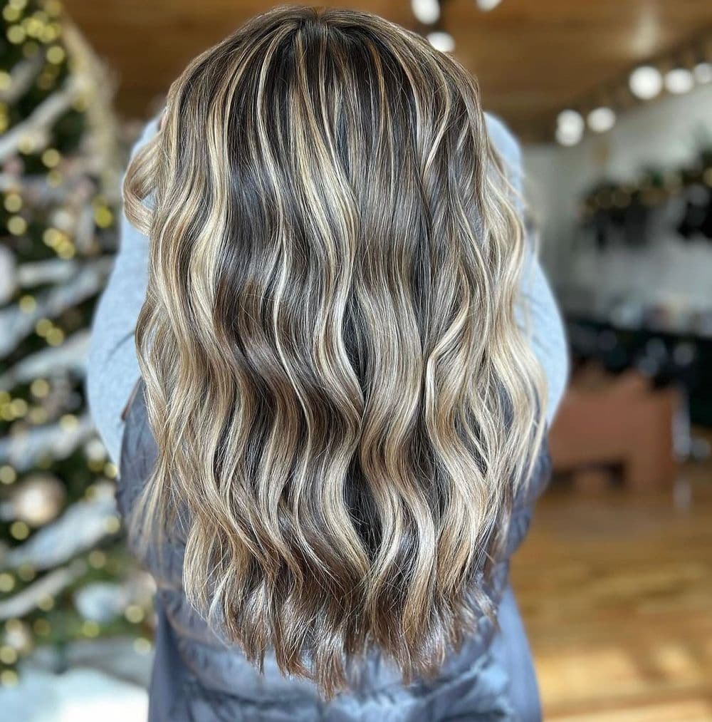 Wavy hair with blonde highlights showcasing a stylish, textured look in a festive setting.